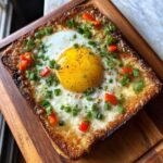 A perfectly cooked Air Fryer Egg and Cheese Toast, topped with fresh chives and diced red peppers.