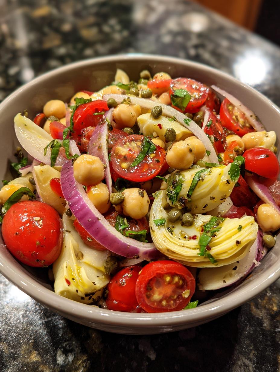 Close-up of Artichoke Tomato Chickpea Salad with cherry tomatoes, chickpeas, red onion, artichoke hearts, and capers.