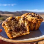 Close-up of a halved banana chocolate chip muffin showing gooey chocolate chips and moist crumb.