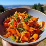 Close-up of a vibrant Carrot Ribbon Salad with Lemon Dressing, garnished with fresh parsley, in a rustic bowl.