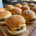 A close-up of several delicious Cheeseburger Sliders with melted cheese and sesame seed buns.