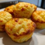 Close-up of golden-brown Cheesy Mashed Potato Muffins with melted cheese on top.