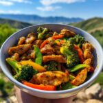 A bowl of Chicken and Veggie Stir Fry Fast Recipe Easy Dinner with chicken pieces, broccoli, bell peppers, and snap peas.