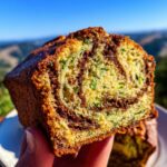 A close-up of a slice of cinnamon swirl zucchini bread, showing the moist crumb and distinct swirls.