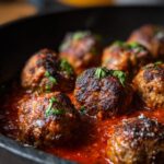 Close-up of juicy Classic Italian Meatballs simmering in a rich tomato sauce, garnished with fresh parsley.
