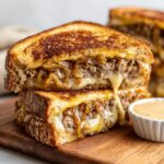 Close-up of two Classic Patty Melts stacked, showing melted cheese, savory ground beef, and caramelized onions.