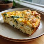 A slice of Cottage Cheese Spinach Crustless Quiche on a plate, showing fluffy egg, spinach, and melted cheese.