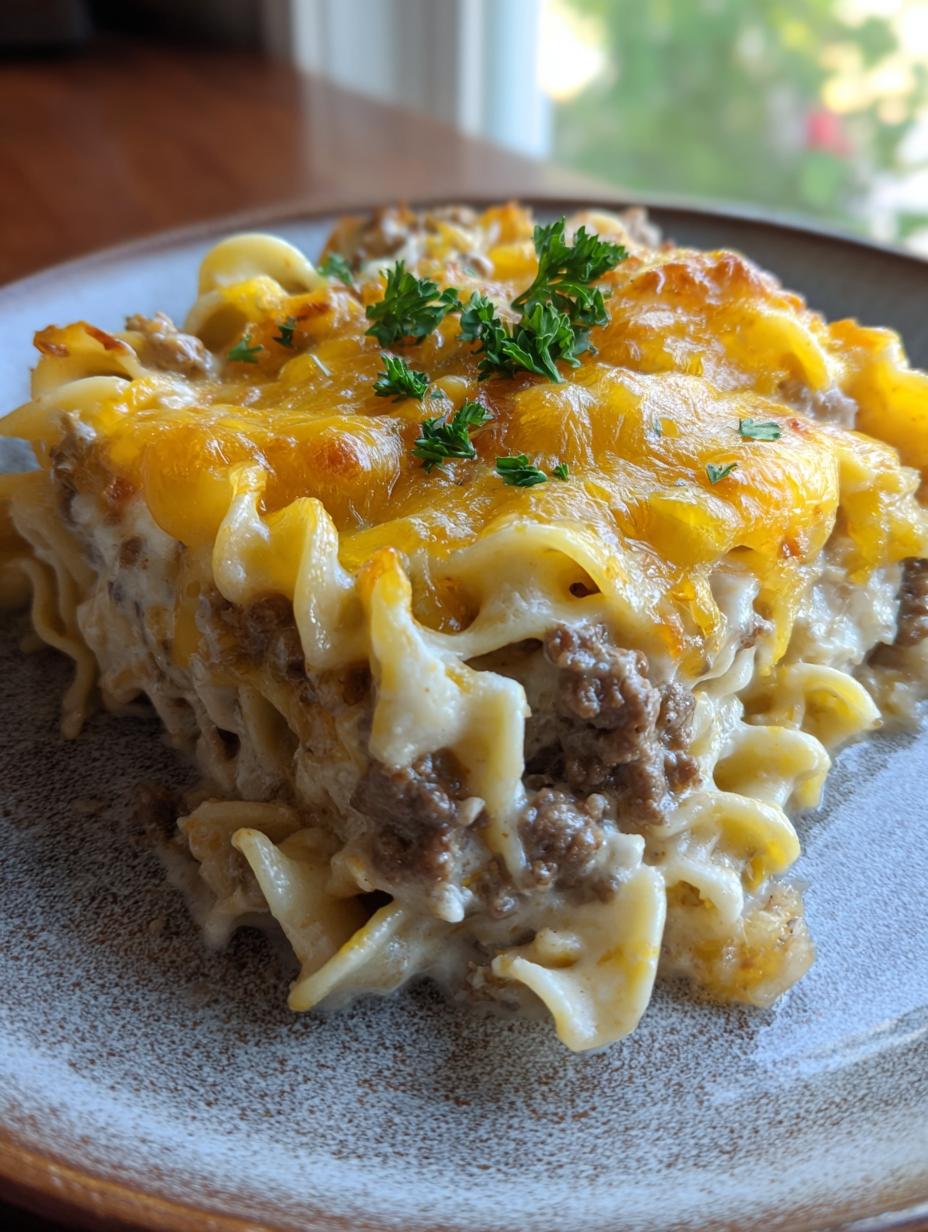 A close-up of a serving of Creamy Beef and Noodle Casserole, topped with melted cheddar cheese and parsley.