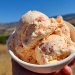 Close-up of creamy Easy Peach Ice Cream No Machine in a bowl with visible peach chunks.