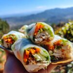 A plate of fresh and light Easy Rice Paper Rolls filled with shredded chicken, carrots, cucumber, and lettuce.