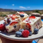 Close-up of three slices of frozen yogurt bark loaded with strawberries and blueberries, garnished with fresh berries.