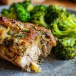 A close-up of a juicy Garlic Lemon Baked Chicken Breast served with vibrant green broccoli.