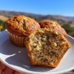 Close-up of soft and fluffy healthy banana oat muffins on a white plate, one muffin is halved to show the texture.