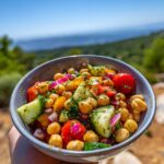 A close-up of a vibrant Mediterranean chickpea salad in a bowl, featuring chickpeas, tomatoes, cucumber, and red onion.
