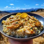 A close-up of a bowl of One Pan Lemon Chicken with Rice, garnished with lemon slices and herbs.