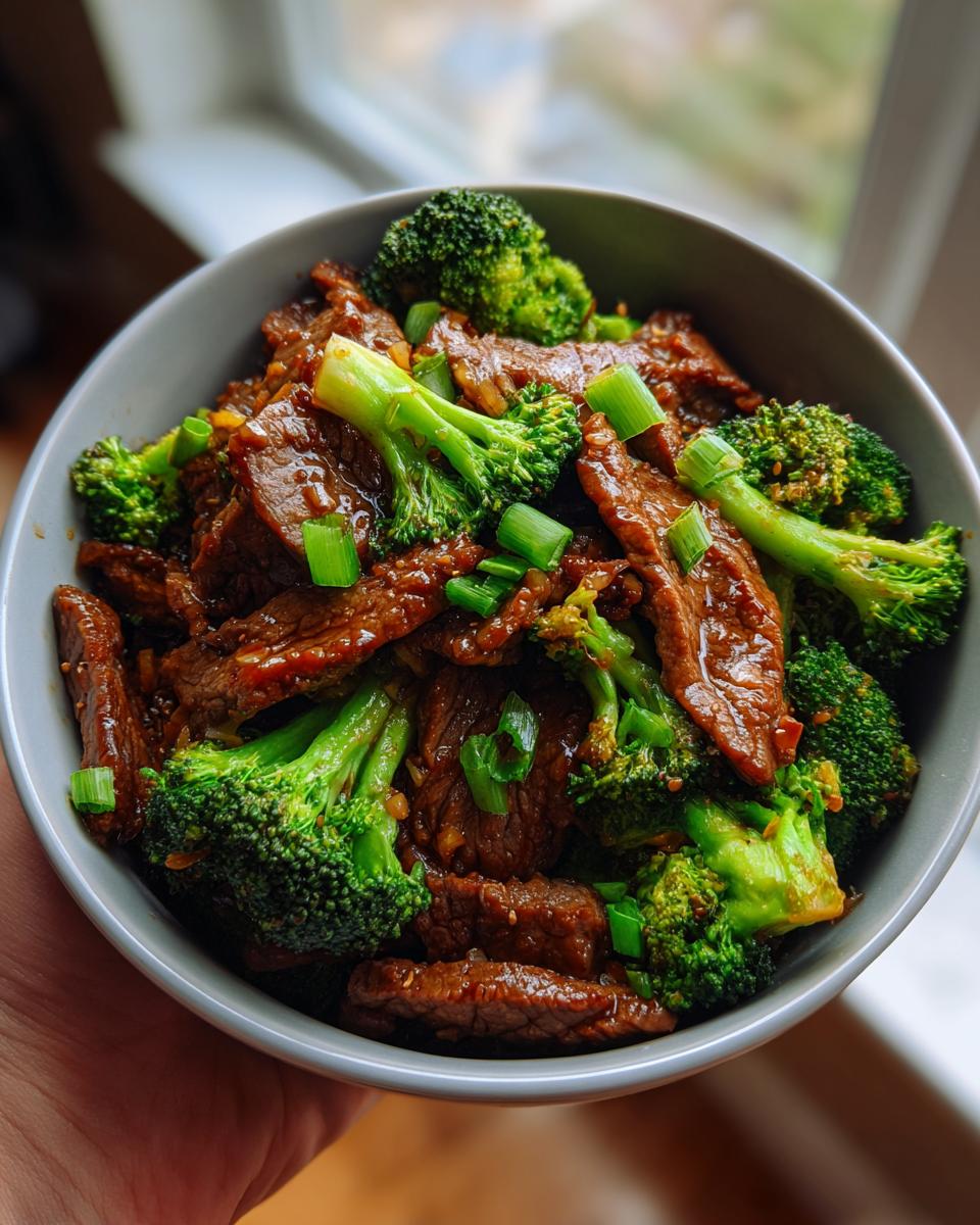 A bowl filled with Quick Healthy Beef and Broccoli Stir Fry, garnished with chopped green onions.