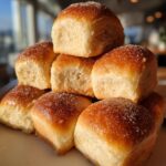 A stack of golden-brown Quick Soft Dinner Rolls, lightly dusted with sugar, ready to be served.