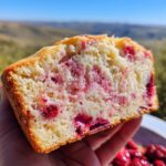 A close-up of a slice of soft strawberry bread with fresh berries baked into it.