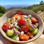 A close-up of a vibrant tomato cucumber feta salad in a rustic bowl, featuring cherry tomatoes, cucumber chunks, feta cheese, and red onion.