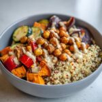Close-up of a Vegan Chickpea and Quinoa Meal Prep Bowl with roasted vegetables and a creamy tahini dressing.