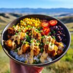 A person holding a bowl of Viral Chicken Bowl Easy Recipe with crispy chicken, rice, corn, tomatoes, and black beans.