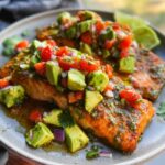 Close-up of two fillets of Baked Cilantro Lime Salmon topped with fresh avocado salsa.