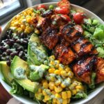A vibrant bowl of BBQ chicken skewer salad with corn, black beans, avocado, tomatoes, and creamy dressing.