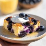 A slice of Blueberry Cottage Cheese Breakfast Bake topped with whipped cream and fresh blueberries.
