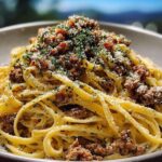 A close-up of a bowl of creamy parmesan beef linguine, topped with crumbled beef and fresh parsley.