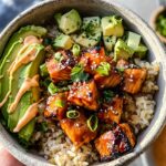 Close-up of an Easy Honey Glazed Salmon Bowl with Rice and Avocado, featuring glazed salmon chunks, sliced avocado, and a drizzle of sauce.