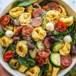 Close-up of a bowl of Fresh Italian Tortellini Pasta Salad with cherry tomatoes, olives, salami, and mozzarella balls.