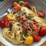A close-up of Fresh Summer Garden Pasta with Tomatoes and Basil, topped with cherry tomatoes and fresh basil.