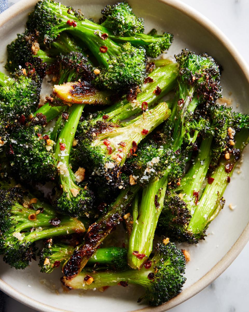 A close-up shot of delicious garlic parmesan roasted broccoli, sprinkled with red pepper flakes and cheese.