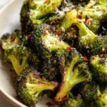 Close-up of perfectly roasted garlic parmesan broccoli florets, sprinkled with chili flakes.