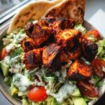 A close-up of Greek chicken tzatziki bowls featuring seasoned chicken, fresh lettuce, tomatoes, cucumber, and creamy tzatziki sauce.