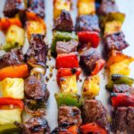 Close-up of perfectly grilled pineapple beef kabobs with colorful bell peppers and onions.