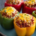 Close-up of colorful ground beef stuffed peppers topped with melted cheddar cheese and parsley.