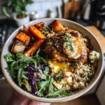 A close-up of a hot honey chicken sheet pan meal served in a bowl with roasted vegetables, quinoa, and greens.