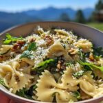 A bowl of Lemon Arugula Pasta Salad featuring farfalle pasta, fresh arugula, walnuts, and grated cheese.