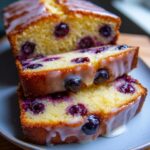 Close-up of stacked slices of lemon blueberry pound cake with a glossy white glaze and visible blueberries.