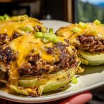Close-up of three oven baked cabbage burgers topped with melted cheddar cheese and green onions.