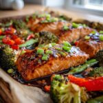 Close-up of glistening sheet pan teriyaki salmon fillets with roasted broccoli, red peppers, and green beans.