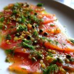 Thinly sliced smoked salmon carpaccio topped with fresh dill, capers, and a light dressing.