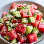 Close-up of a refreshing watermelon feta mint salad with cubed watermelon, cucumber, feta cheese, and mint.