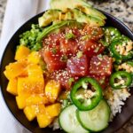 A vibrant Ahi Poke Bowl with fresh tuna, mango, avocado, jalapeños, and cucumber over rice.