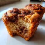 Close-up of a tender Apple Butter Swirl Muffin with a bite taken out, revealing the swirled interior.