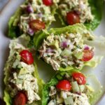 Close-up of Avocado Chicken Salad Lettuce Wraps filled with shredded chicken, avocado, red onion, and cherry tomatoes.