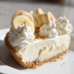 A delicious slice of Banana Cheesecake No Bake Dessert topped with whipped cream and fresh banana slices.