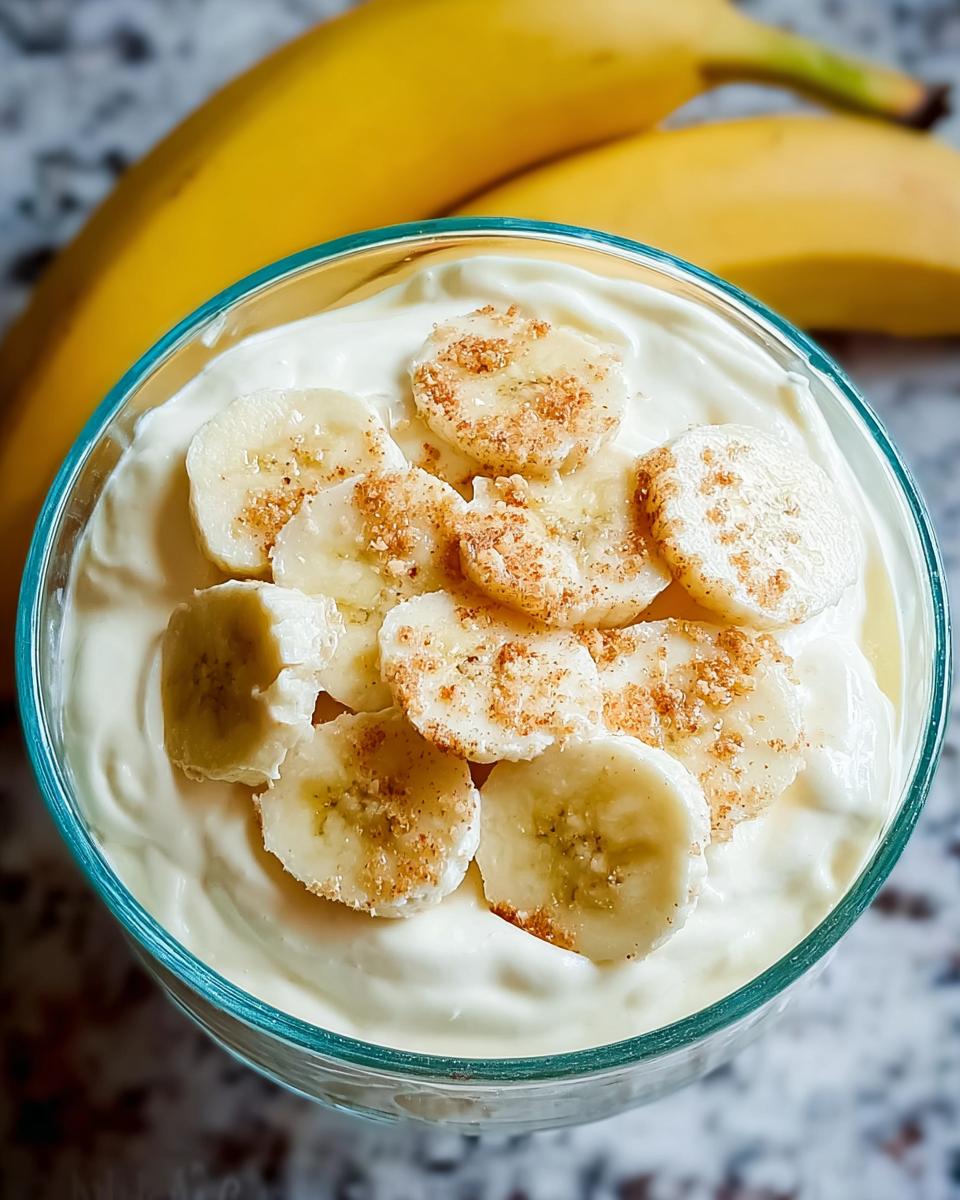 Divine Banana Cream Cheesecake Dip for Easy Desserts 5 Close-up of creamy Banana Cream Cheesecake Dip topped with fresh banana slices and a sprinkle of cinnamon.