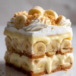 A delicious slice of no bake banana pudding cobbler with layers of bananas, pudding, and cookies, topped with whipped cream.